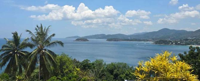 Coastal view of Phuket with palm trees, a small island and surrounding hills