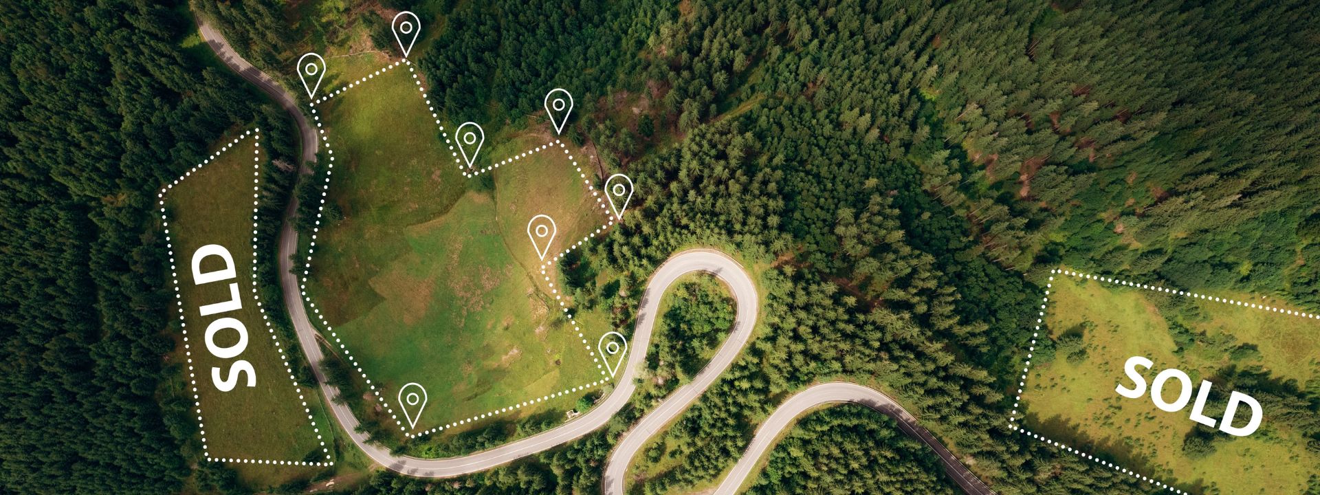 Aerial view of land plots outlined with markers and sold labels in a forested area.
