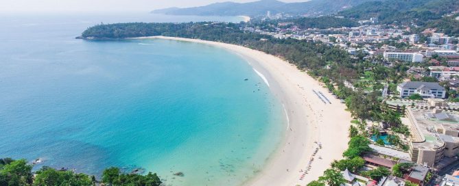 Aerial view of Kata Beach in Phuket with turquoise water, coastline and surrounding town.