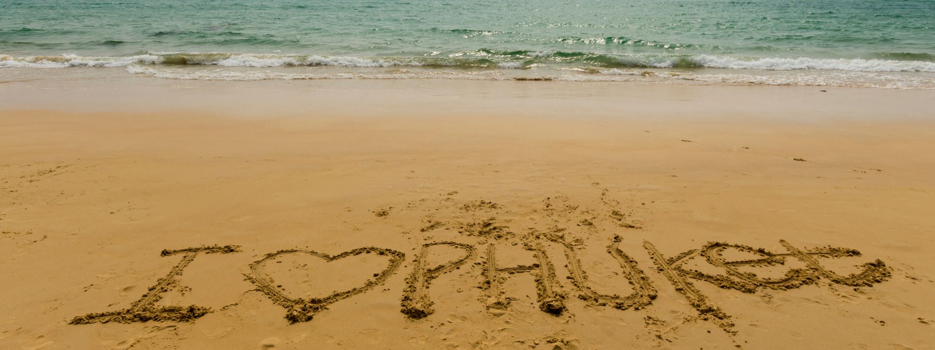 “I love Phuket” written in the sand on a beach in Phuket.
