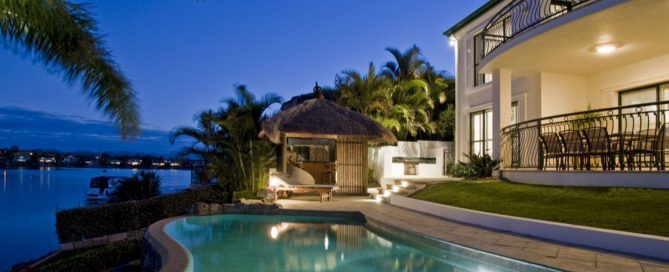 Waterfront villa in Phuket with a pool and outdoor seating at dusk.