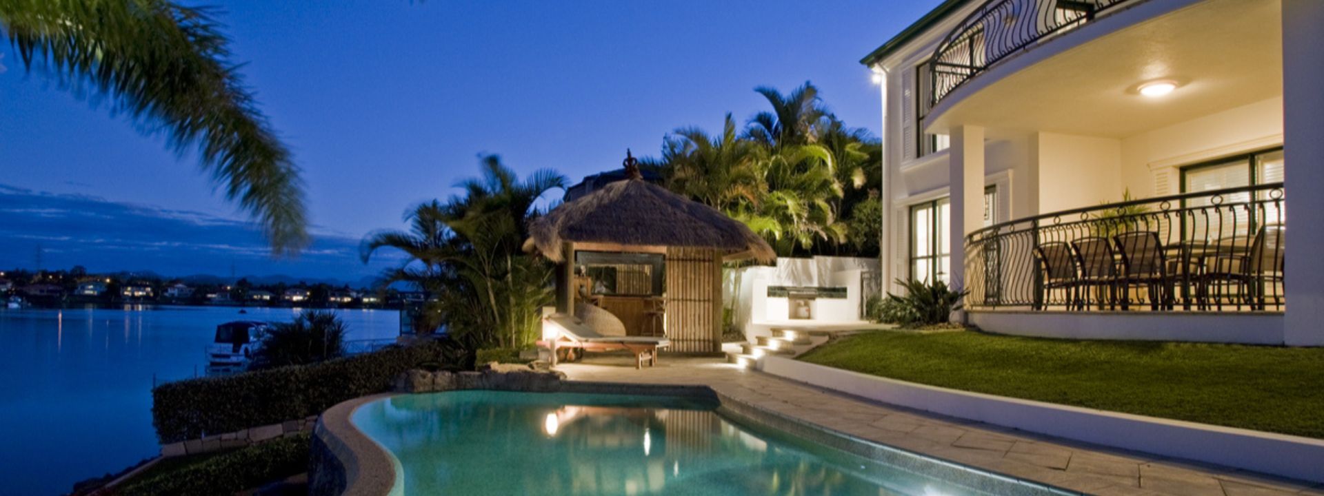 Waterfront villa in Phuket with a pool and outdoor seating at dusk.