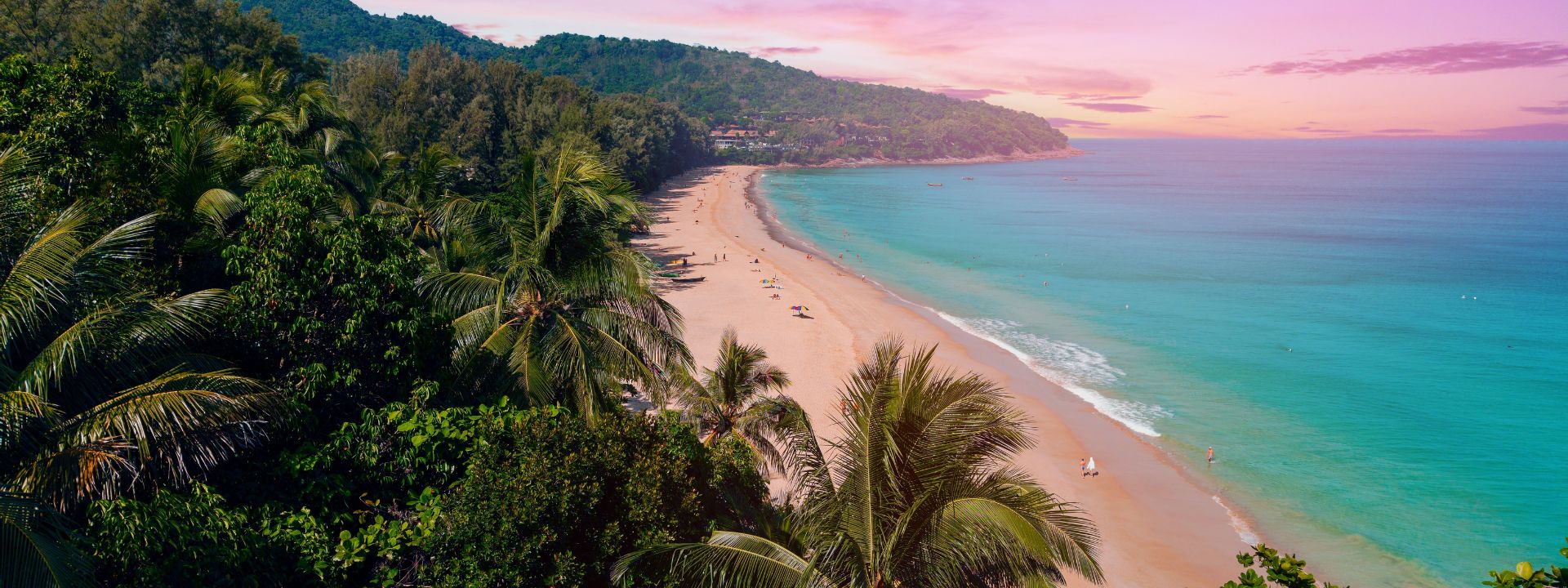 Tropical view of Nai Thon Beach in Phuket with turquoise water, soft sand and lush palm trees at sunset.