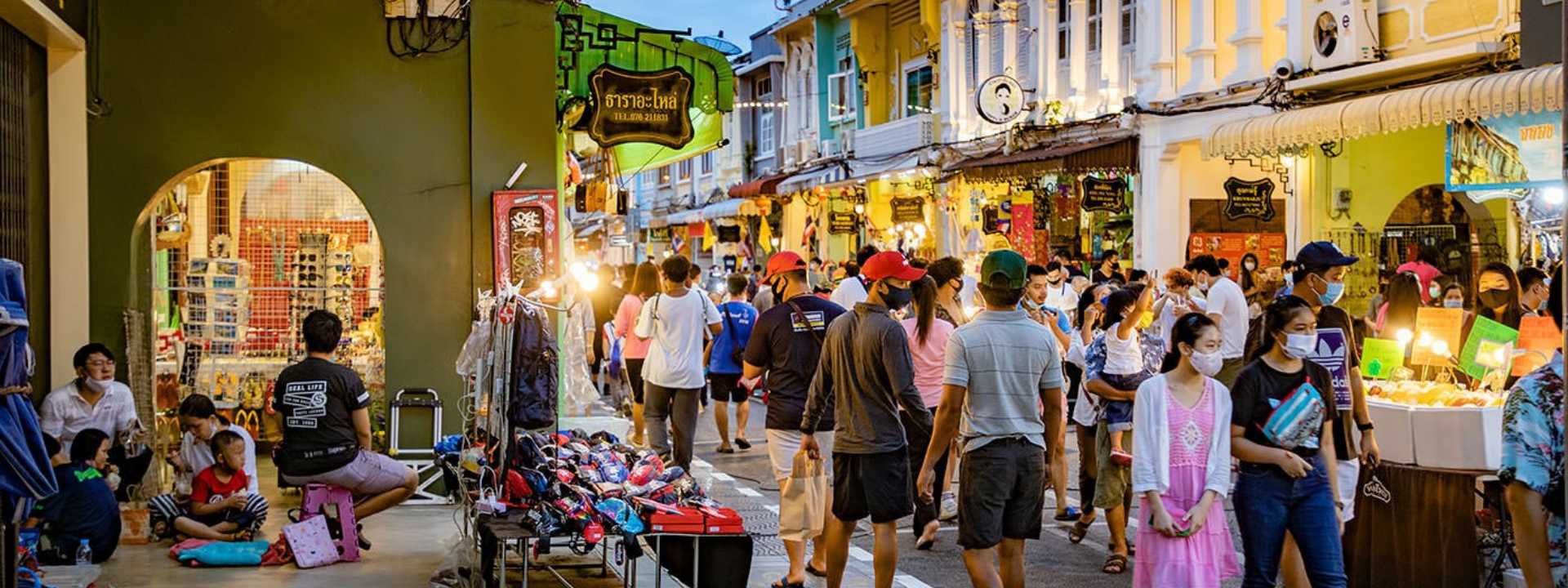 Crowded evening street market with shops and pedestrians in Phuket Old Town