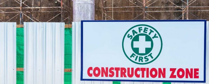 Alt text Construction zone safety sign displayed on a fenced building site with scaffolding in the background