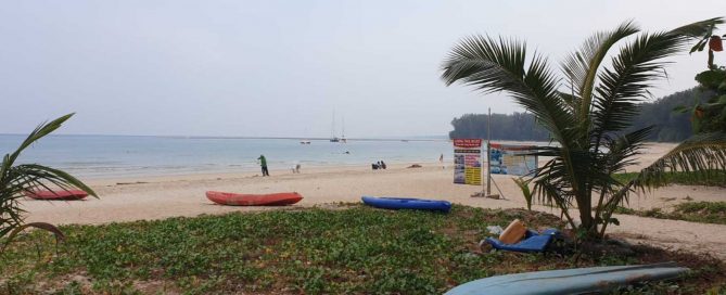 Quiet beach scene at Nai Thon Beach in Phuket with kayaks on the sand and boats offshore
