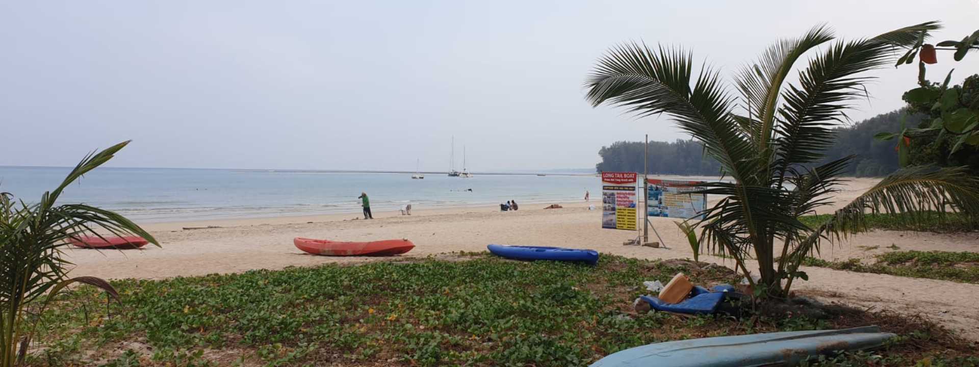 Quiet beach scene at Nai Thon Beach in Phuket with kayaks on the sand and boats offshore