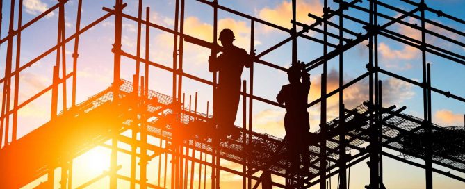 Construction workers on scaffolding at a building site in Phuket during sunset