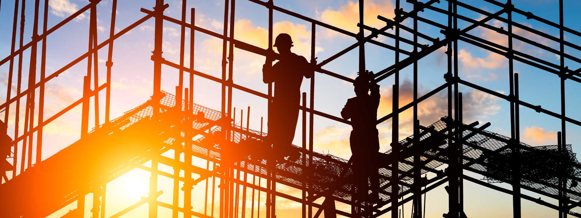 Construction workers on scaffolding at a building site in Phuket during sunset