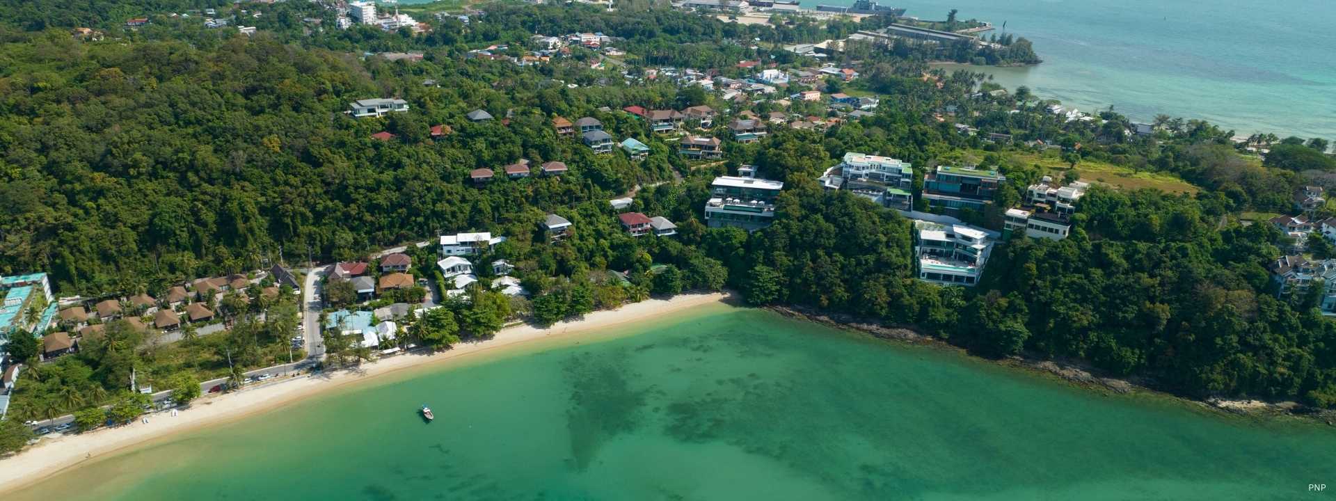 Aerial view of a secluded Phuket bay with hillside villas and low-density coastal development