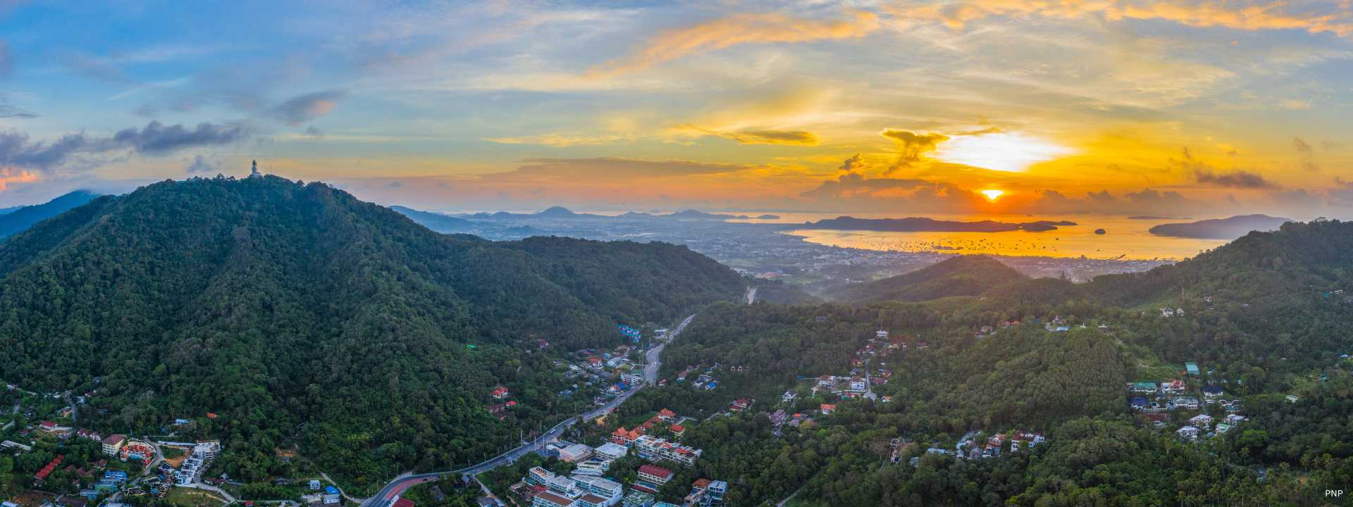 View across inland hills and coastal areas of Phuket at sunset.