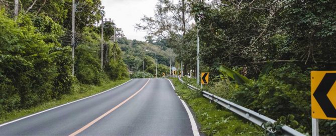 Winding inland road in Phuket surrounded by dense tropical vegetation and forested hills