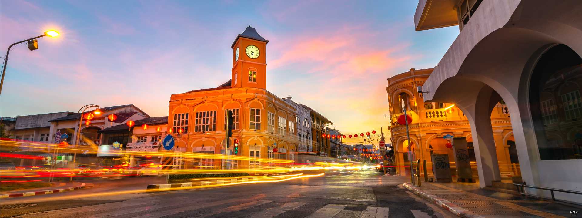 Phuket Old Town clock tower and Sino-Portuguese buildings at dusk with traffic light trails