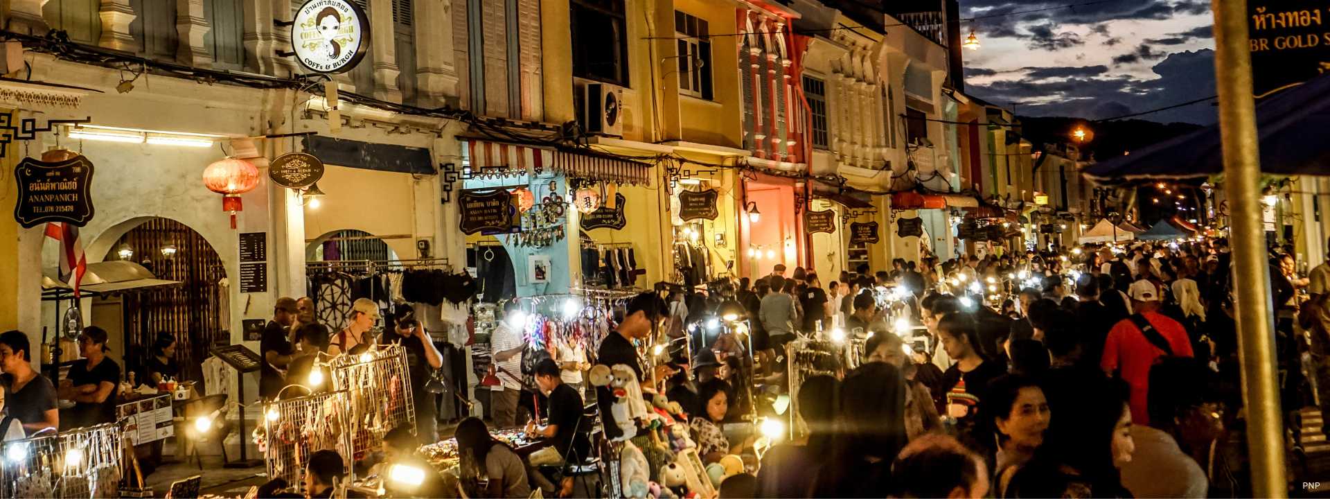 Crowded night market along Phuket Old Town street with shops, street vendors, and evening crowds