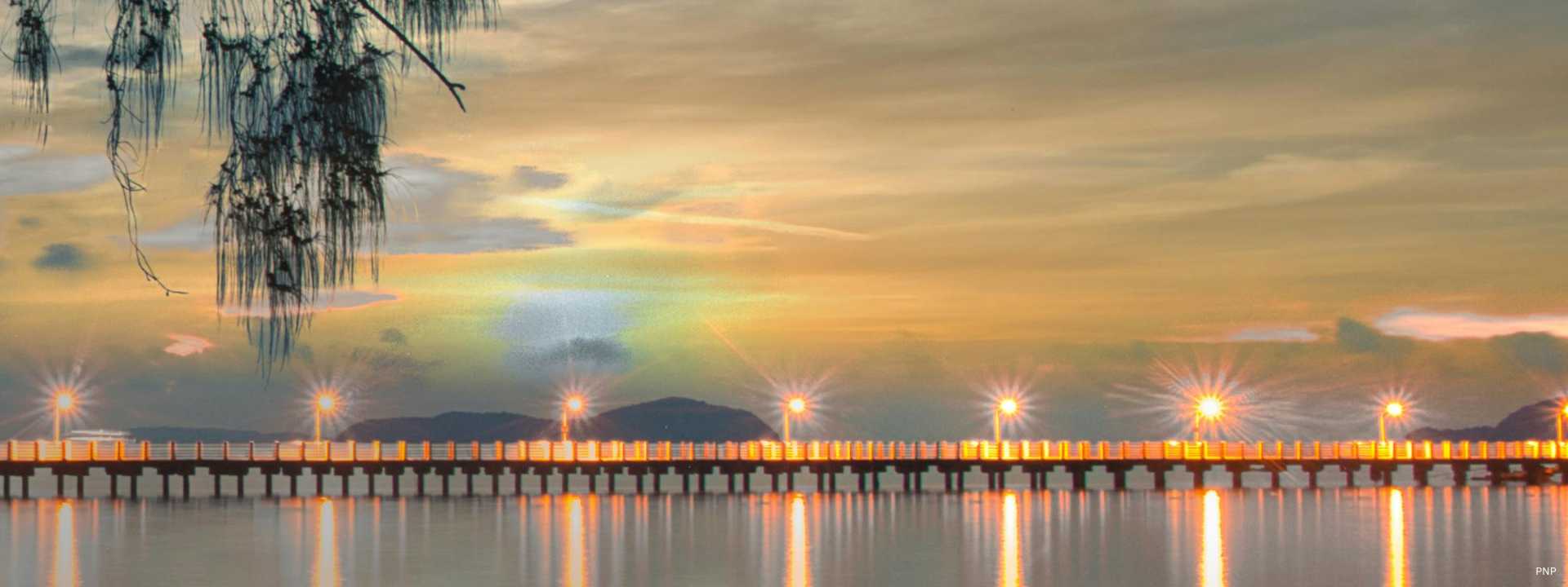 Pier in Phuket at dusk with illuminated lights reflecting across calm water