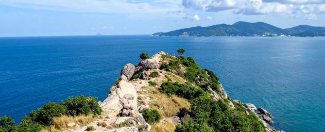 Rocky coastal headland in Phuket overlooking the Andaman Sea with distant hills
