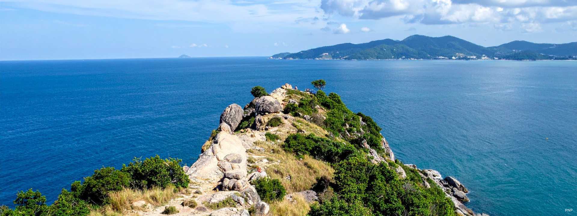 Rocky coastal headland in Phuket overlooking the Andaman Sea with distant hills