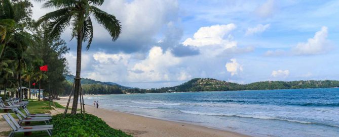 Peaceful beachfront in Bang Tao, Phuket with palm trees, sandy shoreline, and calm sea along a residential coastal area
