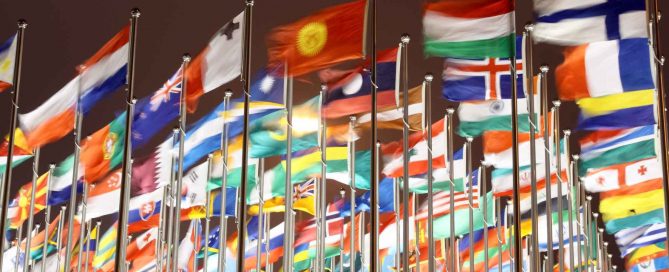 Multiple international flags flying on flagpoles, representing different countries and global diversity