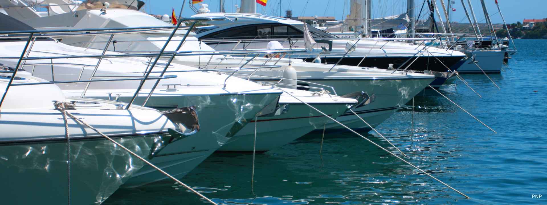 Luxury yachts moored side by side in a marina on a sunny day