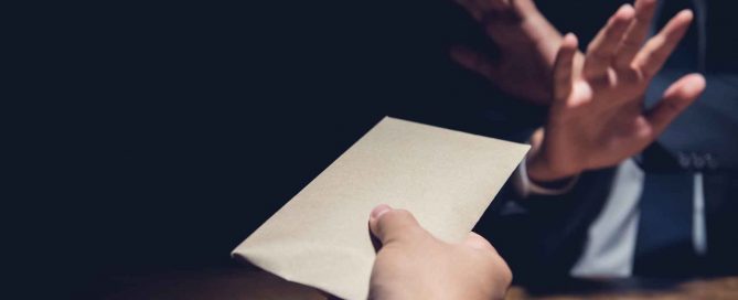 Person holding up a hand to refuse an envelope being offered