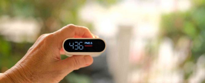 Handheld PM2.5 air quality monitor showing pollution levels in Phuket