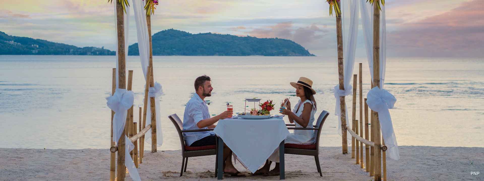 Foreign couple enjoying dinner on a beach in Phuket representing the lifestyle attracting long-stay visa applicants