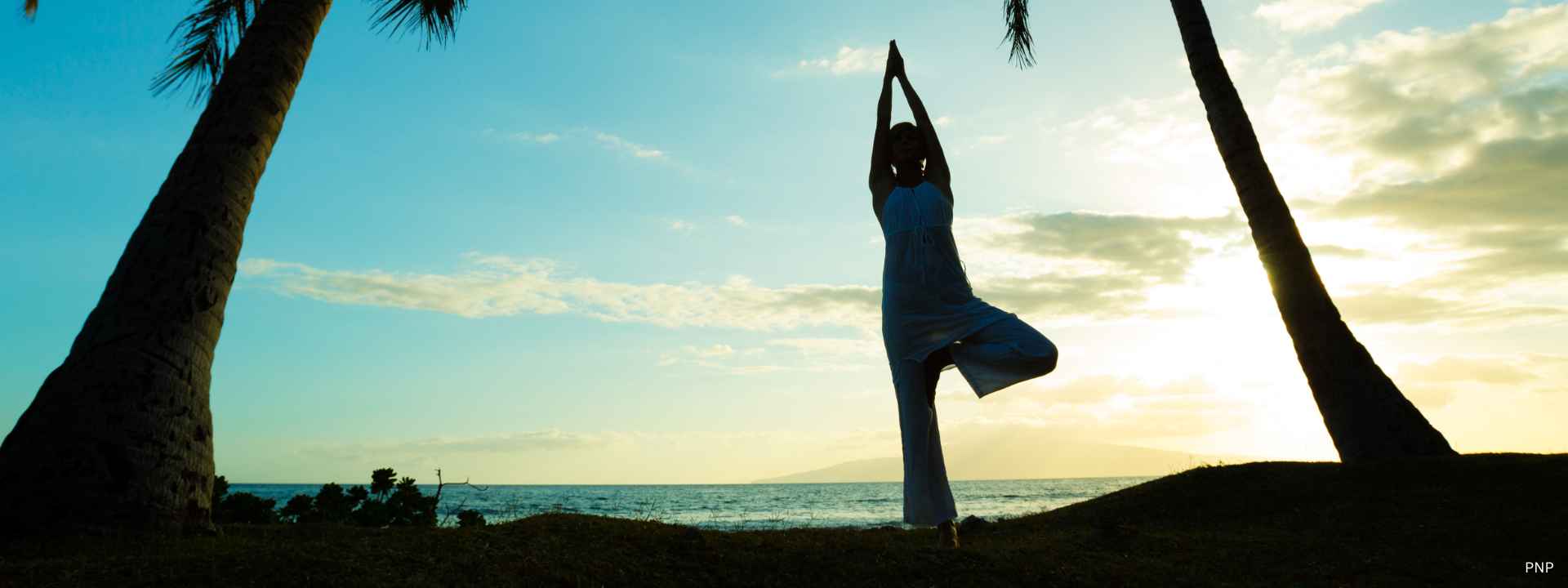 Person practicing yoga at sunrise on a tropical Phuket beach, reflecting a healthy and balanced lifestyle